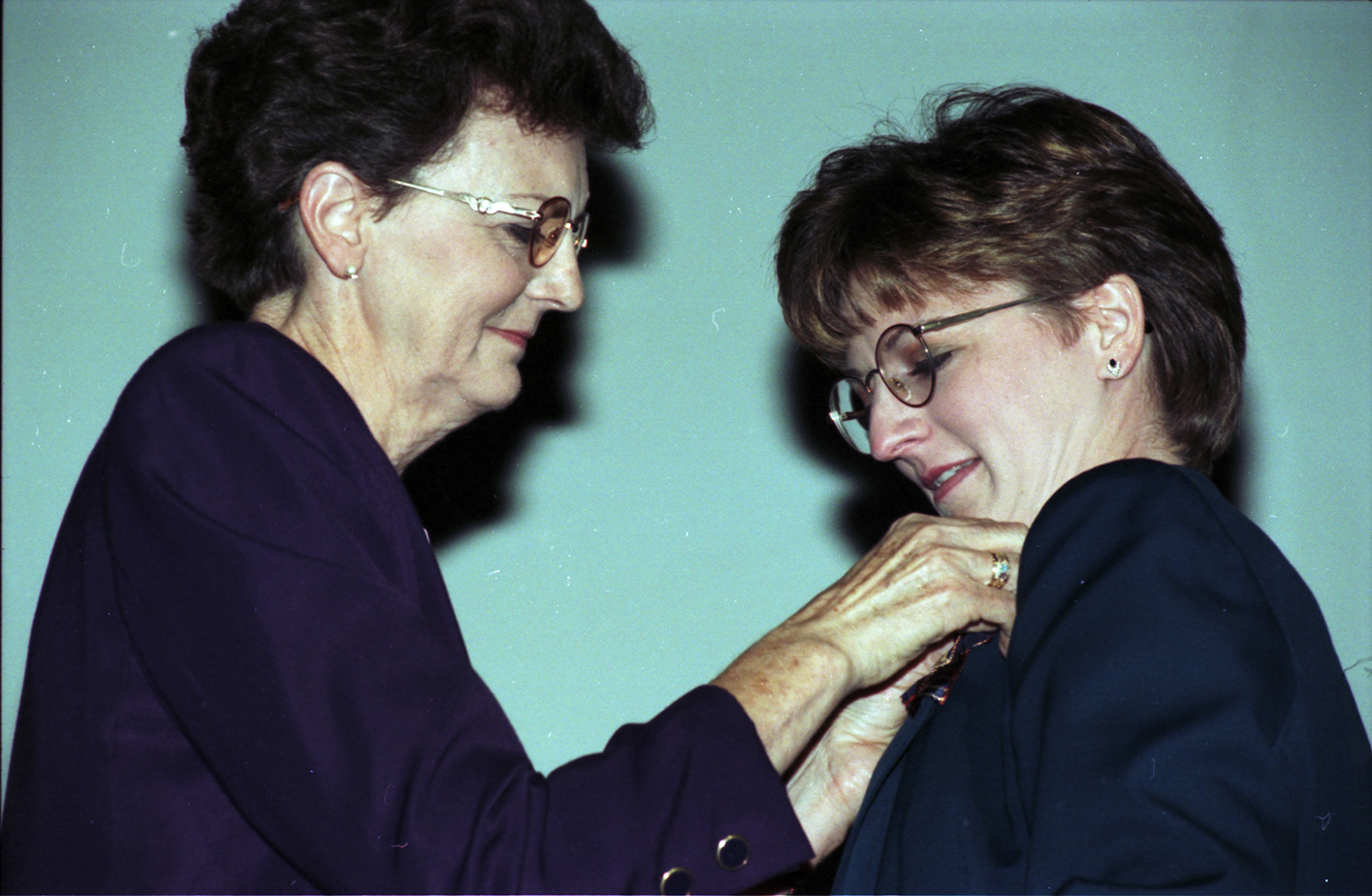 A nursing faculty member pins a graduate of the University of Texas at Arlington School of Nursing at a pinning ceremony.